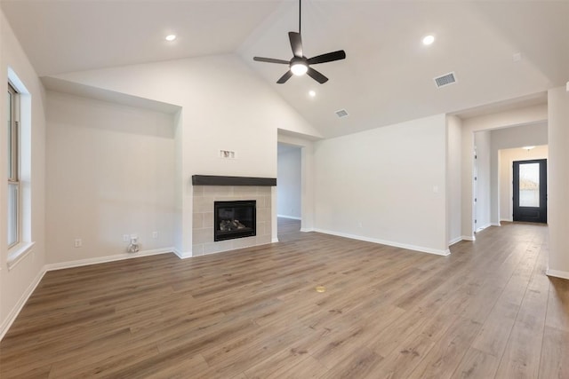 unfurnished living room featuring high vaulted ceiling, ceiling fan, hardwood / wood-style floors, and a tile fireplace