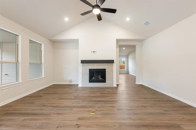 unfurnished living room featuring a tiled fireplace, ceiling fan, wood-type flooring, and vaulted ceiling