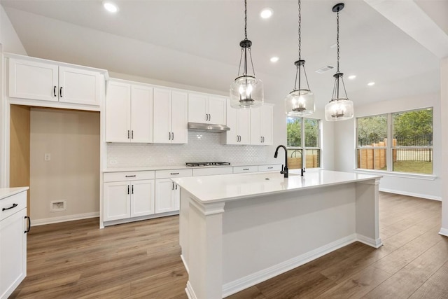 kitchen featuring white cabinetry, a kitchen island with sink, and decorative light fixtures