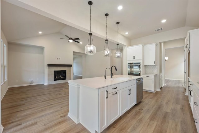 kitchen featuring decorative backsplash, ceiling fan, sink, white cabinetry, and an island with sink