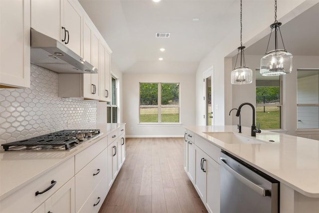 kitchen with sink, an island with sink, lofted ceiling, white cabinets, and appliances with stainless steel finishes