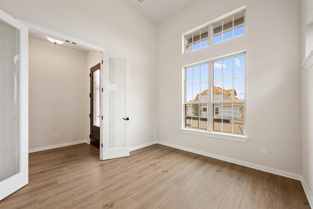 unfurnished room with french doors and light hardwood / wood-style floors