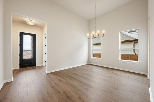 entrance foyer featuring hardwood / wood-style flooring, lofted ceiling, and an inviting chandelier