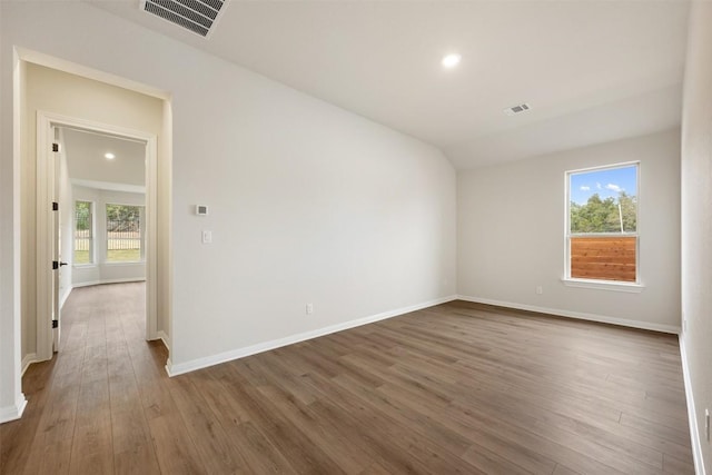 spare room with dark hardwood / wood-style floors and vaulted ceiling