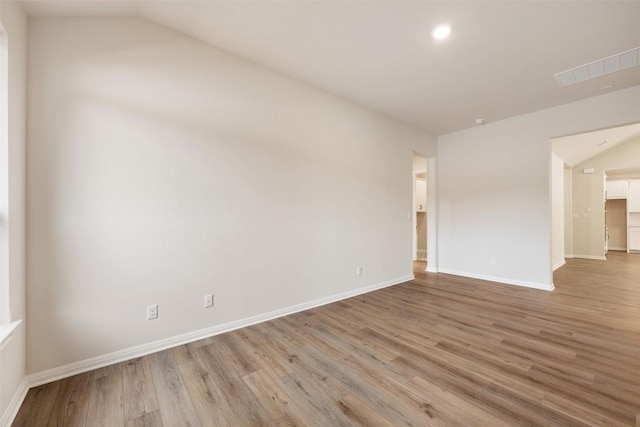 empty room with light hardwood / wood-style floors and vaulted ceiling