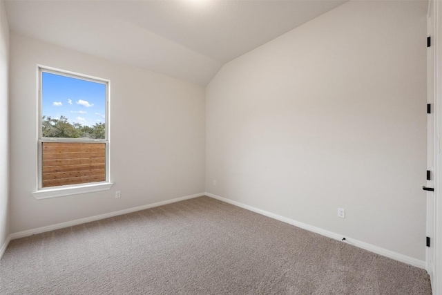 carpeted spare room featuring lofted ceiling