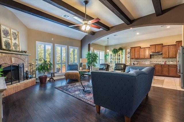 living room with ceiling fan, sink, a fireplace, and light hardwood / wood-style flooring