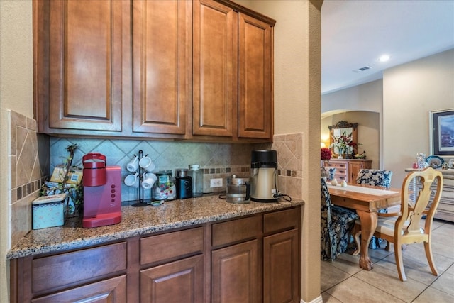 kitchen featuring light tile patterned floors, dark stone counters, and tasteful backsplash