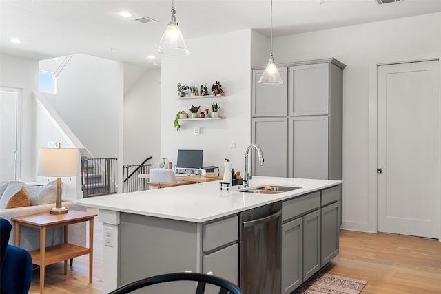 kitchen featuring dishwasher, light hardwood / wood-style floors, a kitchen island with sink, and sink