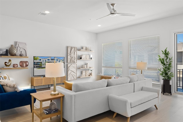 living room with light wood-type flooring, ceiling fan, and a healthy amount of sunlight