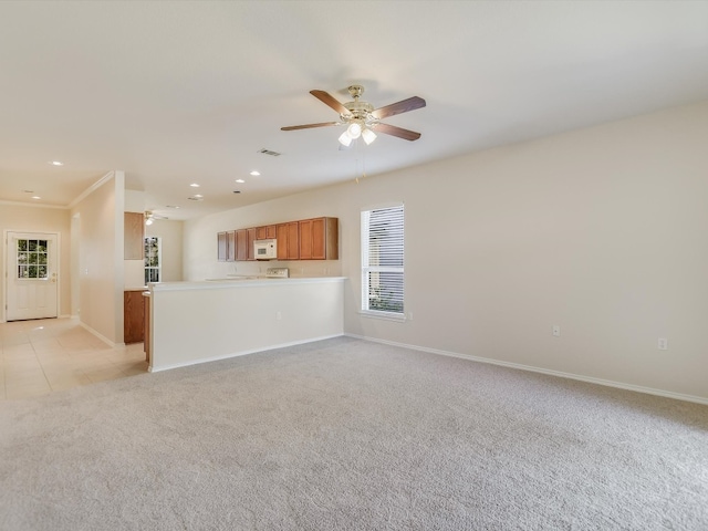 unfurnished living room with ceiling fan, light colored carpet, and crown molding