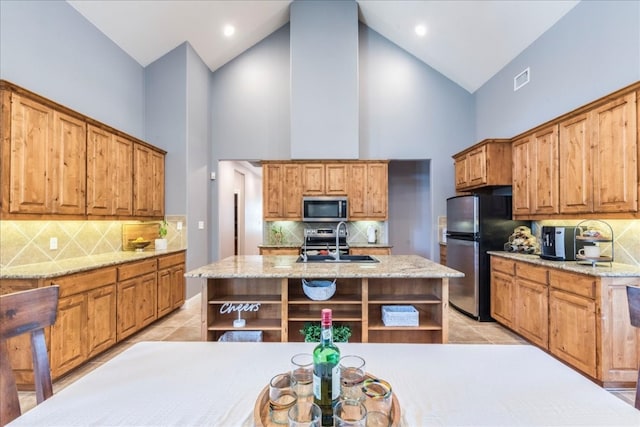 kitchen with a center island with sink, stainless steel appliances, and high vaulted ceiling