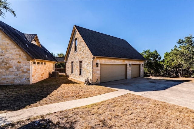 view of side of property with a garage and central AC