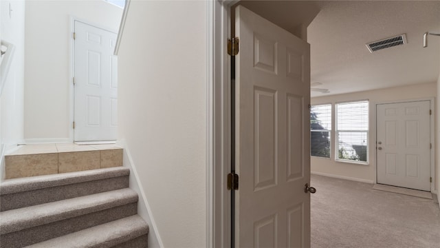 staircase featuring carpet floors and a textured ceiling