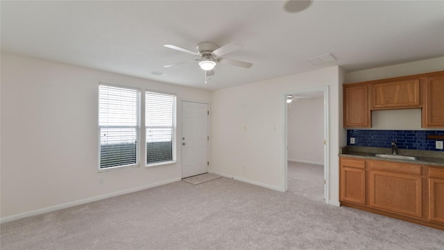 418 Shadow Pt, San Marcos, TX 78666 - kitchen featuring brown cabinets, decorative backsplash, light colored carpet, a sink, and ceiling fan