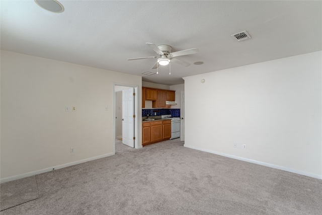 unfurnished living room featuring ceiling fan, sink, and light carpet