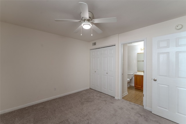 unfurnished bedroom with light carpet, ensuite bath, ceiling fan, and a closet