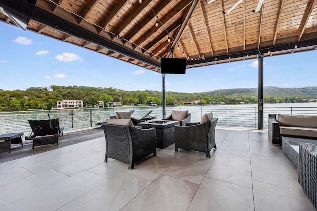 view of patio featuring an outdoor living space with a fire pit and a water view