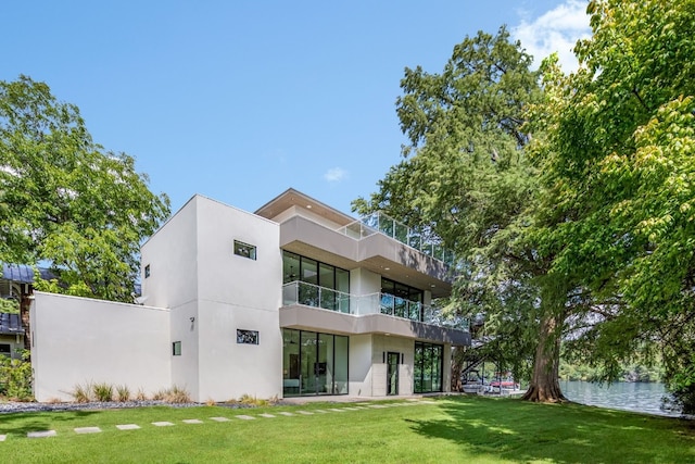 back of property with a yard and a balcony