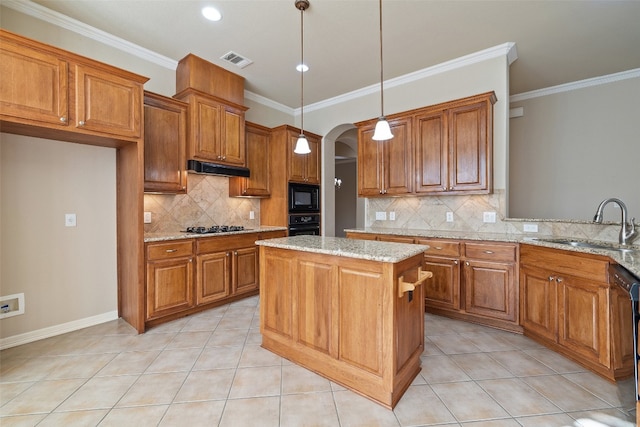 kitchen featuring light stone counters, sink, a kitchen island, decorative light fixtures, and black appliances