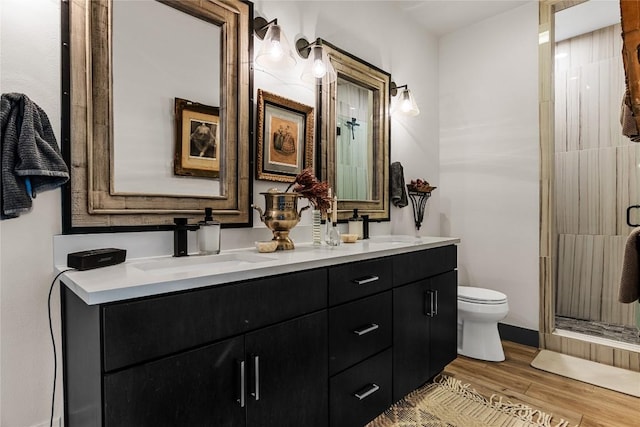 bathroom with vanity, toilet, wood-type flooring, and a shower with shower door