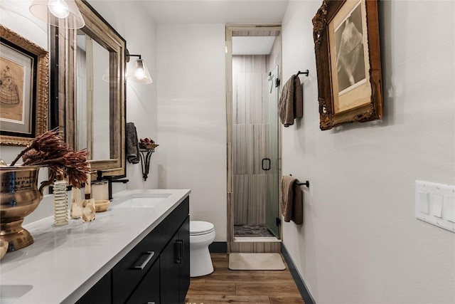 bathroom with hardwood / wood-style floors, vanity, a shower with shower door, and toilet