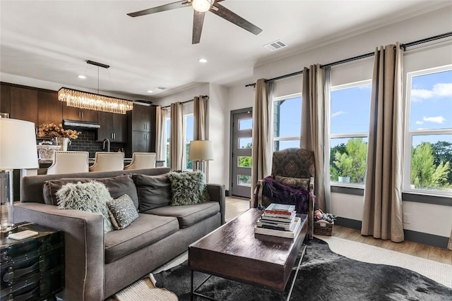 living room with ceiling fan with notable chandelier and light wood-type flooring