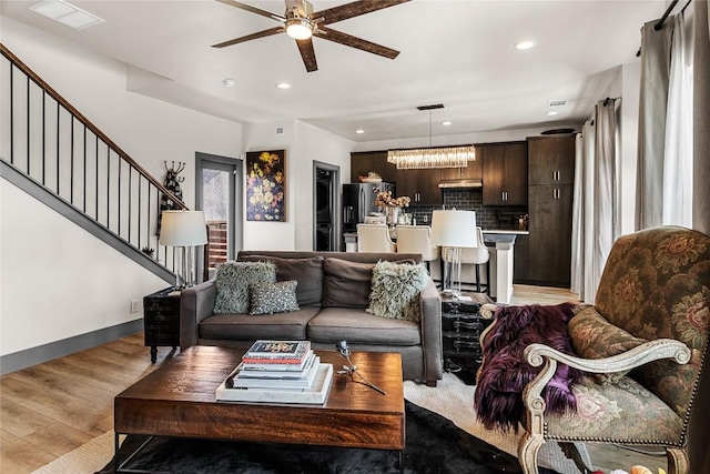 living room featuring ceiling fan with notable chandelier, light hardwood / wood-style flooring, and a healthy amount of sunlight