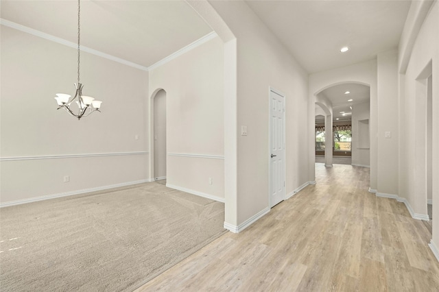 hall featuring an inviting chandelier, light wood-type flooring, and ornamental molding