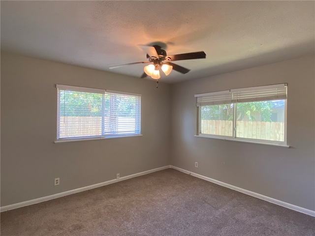 carpeted spare room with a textured ceiling, ceiling fan, and a wealth of natural light