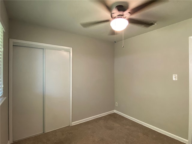 unfurnished bedroom featuring ceiling fan, a closet, and dark colored carpet