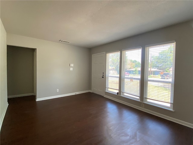 empty room with a textured ceiling and dark hardwood / wood-style floors