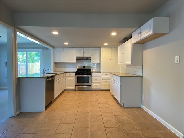 kitchen featuring decorative backsplash, white cabinets, stainless steel appliances, dark stone counters, and sink