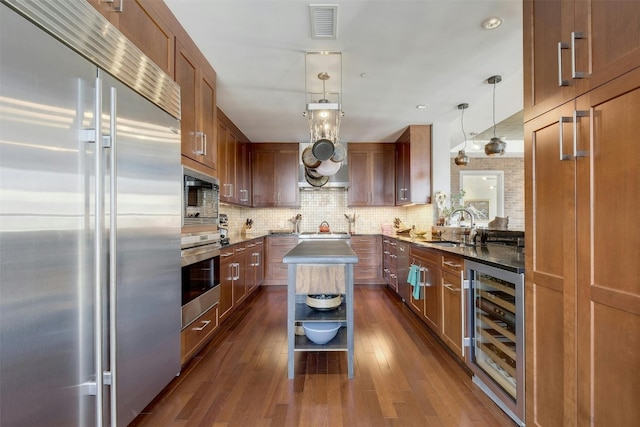 kitchen featuring wine cooler, decorative light fixtures, built in appliances, a center island, and dark hardwood / wood-style flooring