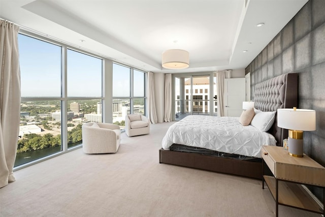 bedroom with light colored carpet and a tray ceiling