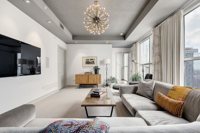 carpeted living room with a chandelier, a textured ceiling, and a raised ceiling