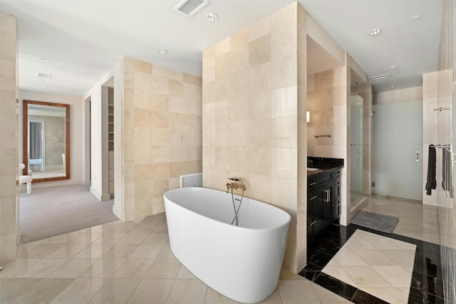 bathroom featuring independent shower and bath, tile walls, vanity, and tile patterned floors