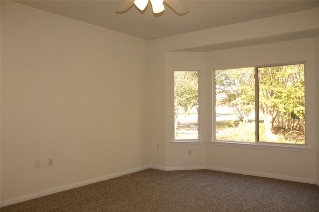 carpeted empty room featuring a ceiling fan and baseboards