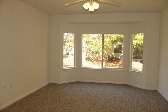 carpeted empty room featuring ceiling fan and baseboards