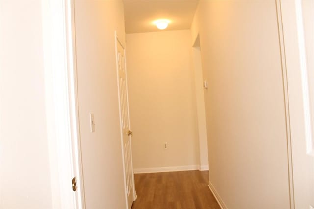 hall with baseboards and wood finished floors