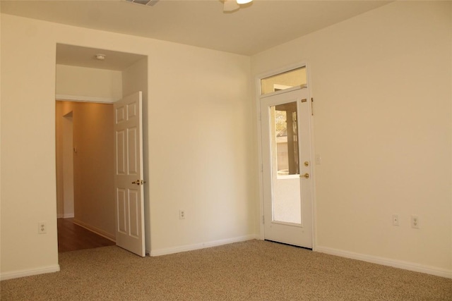 carpeted empty room featuring a wealth of natural light, visible vents, and baseboards