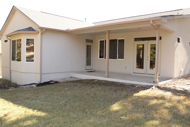 back of property featuring a shingled roof, a lawn, a patio area, and stucco siding