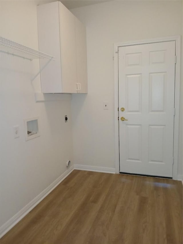 clothes washing area featuring hookup for an electric dryer, washer hookup, wood finished floors, baseboards, and cabinet space