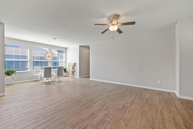 empty room featuring light hardwood / wood-style flooring and ceiling fan with notable chandelier