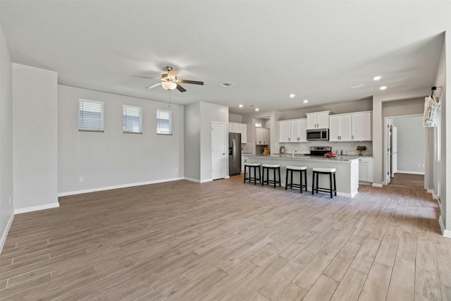 unfurnished living room featuring ceiling fan and light hardwood / wood-style floors