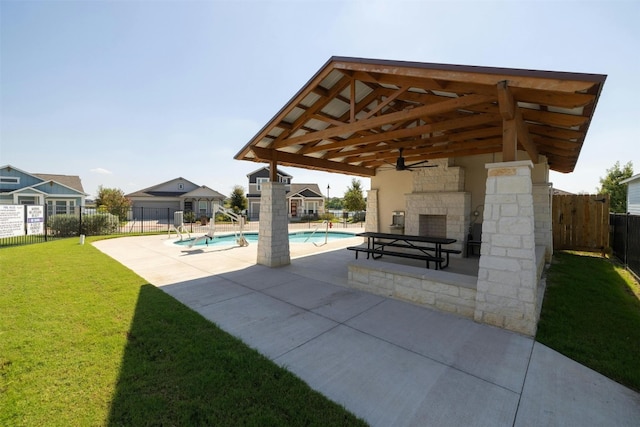 view of patio / terrace featuring an outdoor stone fireplace, ceiling fan, and a community pool