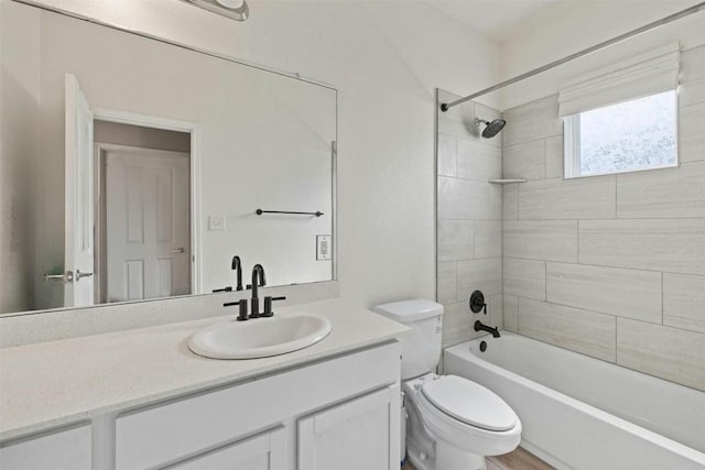 full bathroom featuring vanity, tiled shower / bath combo, and toilet