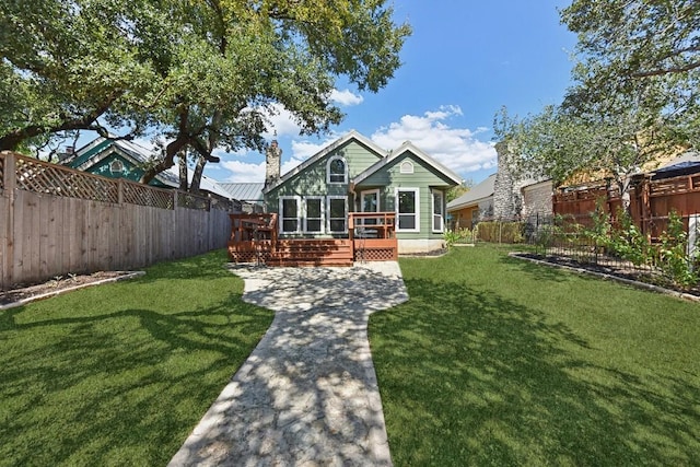 rear view of property featuring a deck, a fenced backyard, a lawn, and a chimney