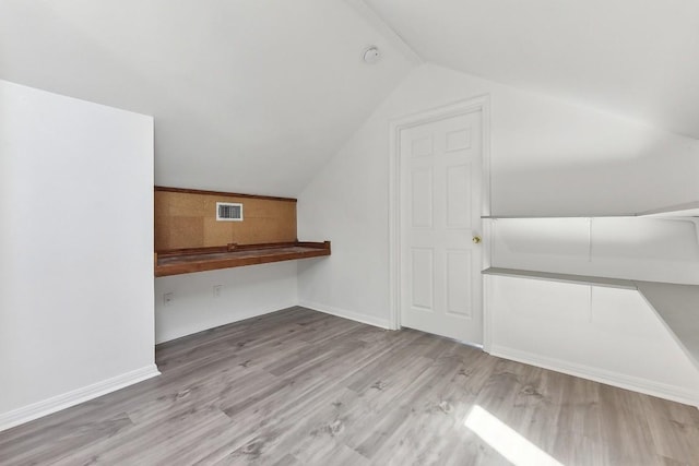 bonus room with vaulted ceiling and light wood-type flooring