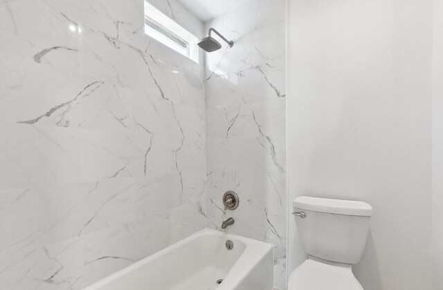 bathroom featuring tiled shower / bath combo and toilet